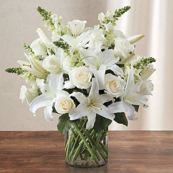 White lilies and roses arranged in a clear glass vase