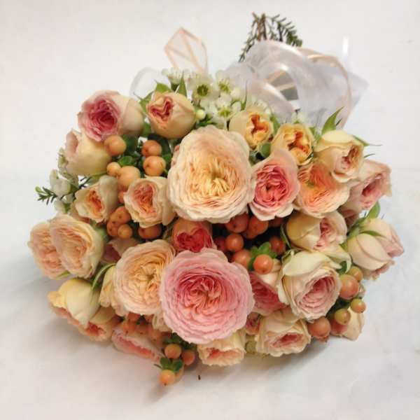 Bouquet of blush and peach roses with small white flowers