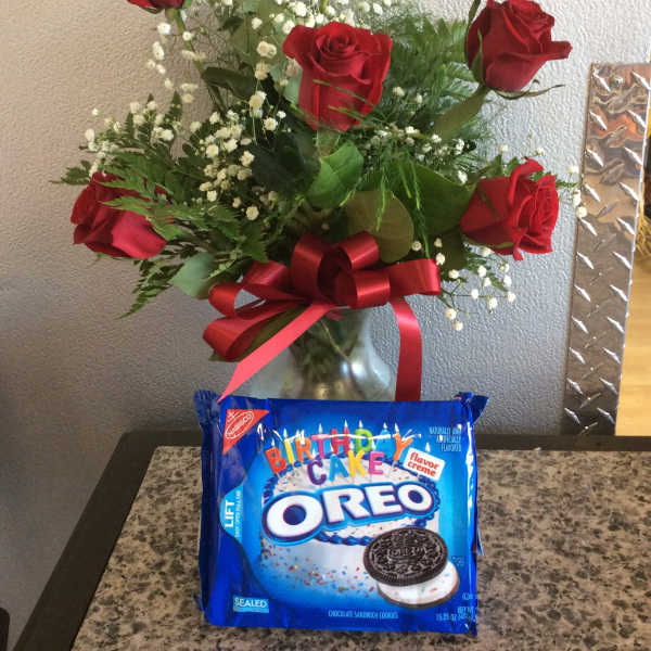 Red roses in a glass vase with a red ribbon and a birthday Oreo cookie package