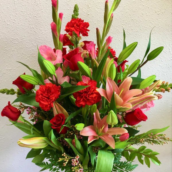 Tall bouquet of red and pink flowers in a clear glass vase