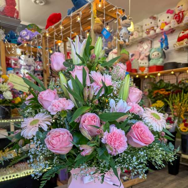 Pink roses and lilies arranged in a pink gift box