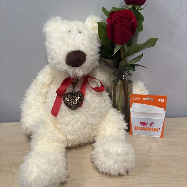 White teddy bear beside two red roses in a glass vase and a Dunkin' gift card