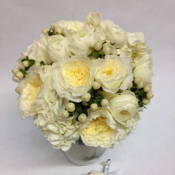 White rose bouquet in a glass vase with a matching boutonniere below