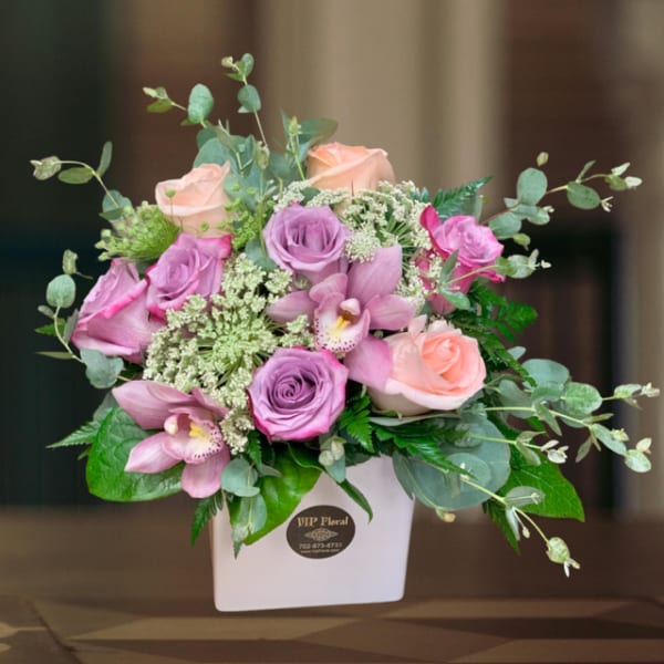 Pink and peach roses with orchids in a white box