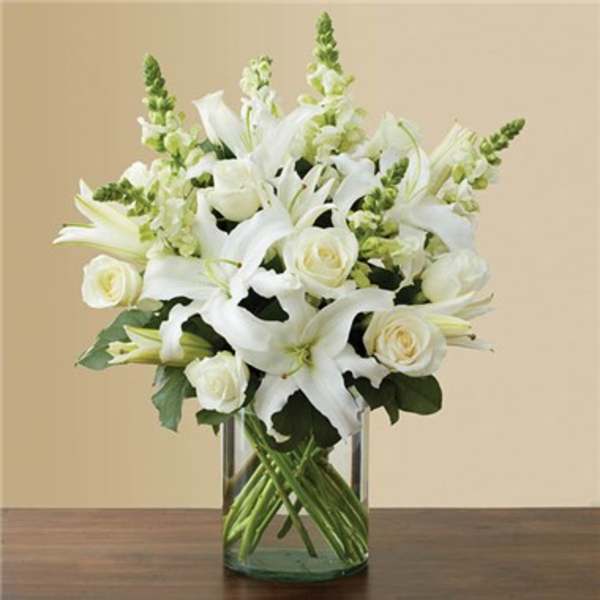 White lilies and roses arranged in a clear glass vase