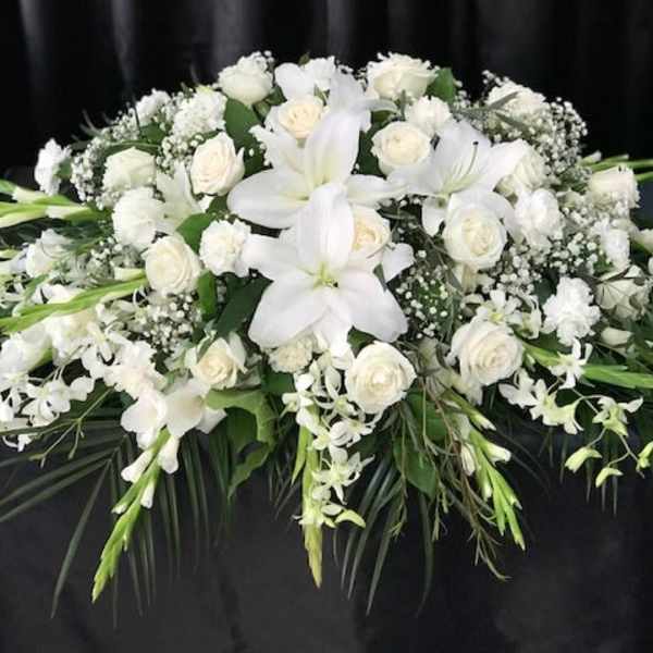 White floral casket spray with lilies and roses