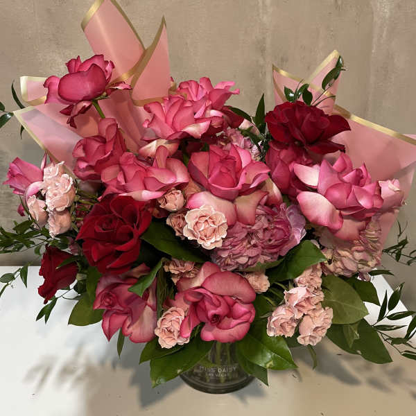 Pink and red rose bouquet in a glass vase with pink wrap