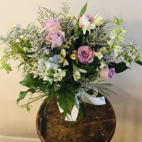 Bouquet of pink and lavender roses with white flowers in a glass vase