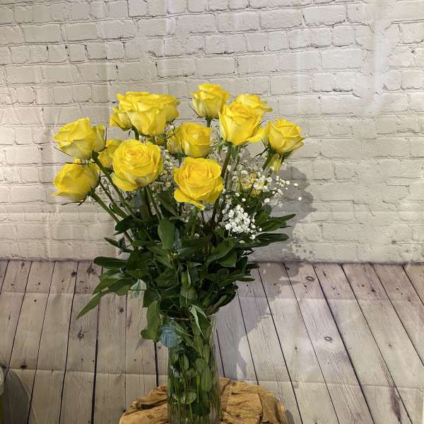 Yellow roses in a clear glass vase with white filler flowers