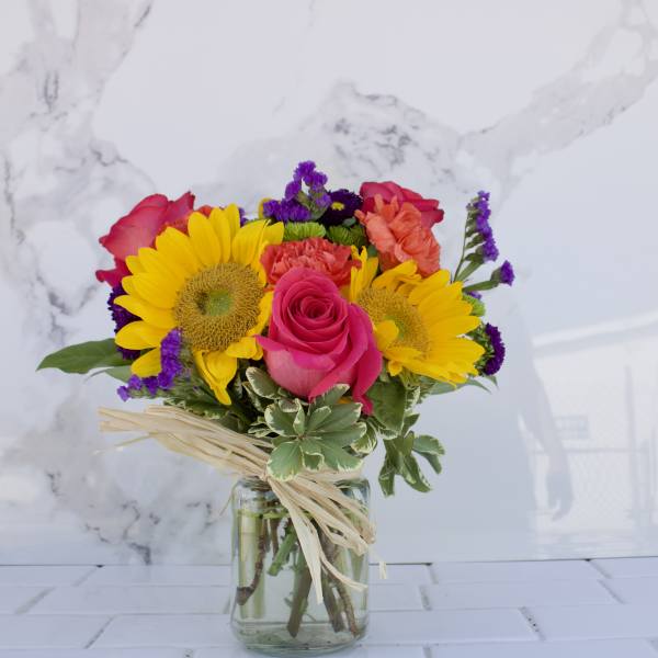 Bouquet of sunflowers and pink roses in a glass vase