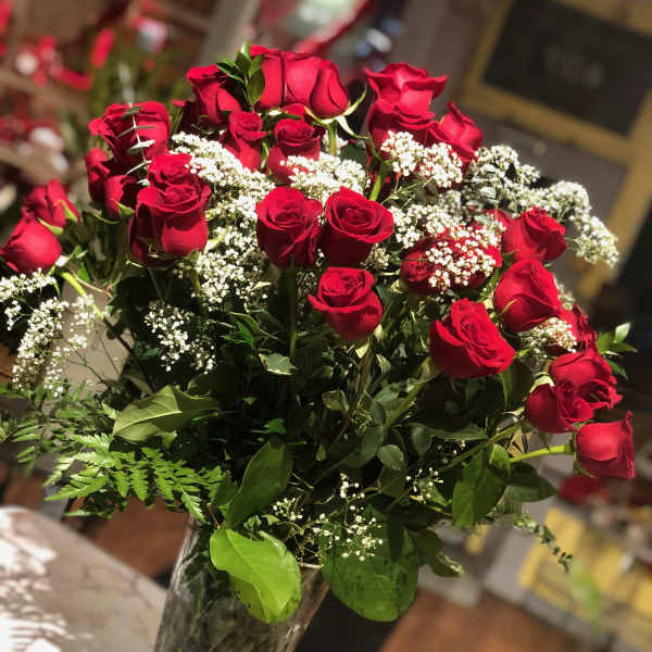 Red roses arranged in a clear glass vase with white baby's breath