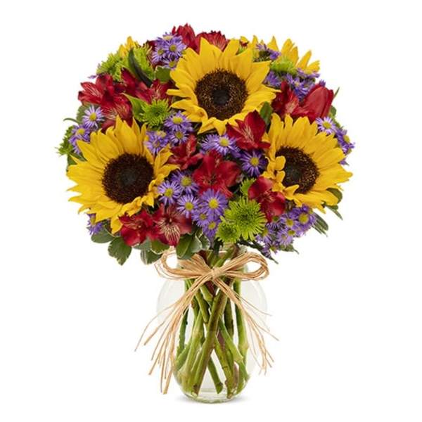 Bouquet of sunflowers, red flowers, and purple daisies in a glass vase