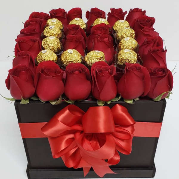 Red roses and gold-wrapped chocolates arranged in a black gift box with a red bow.