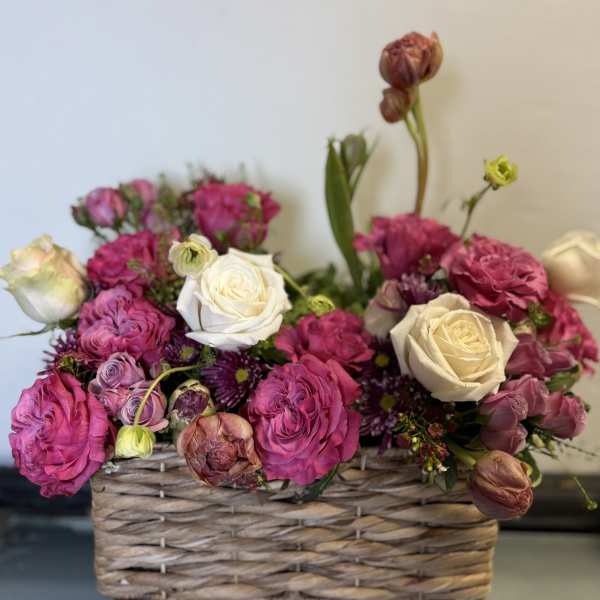 Pink and white roses arranged in a woven basket