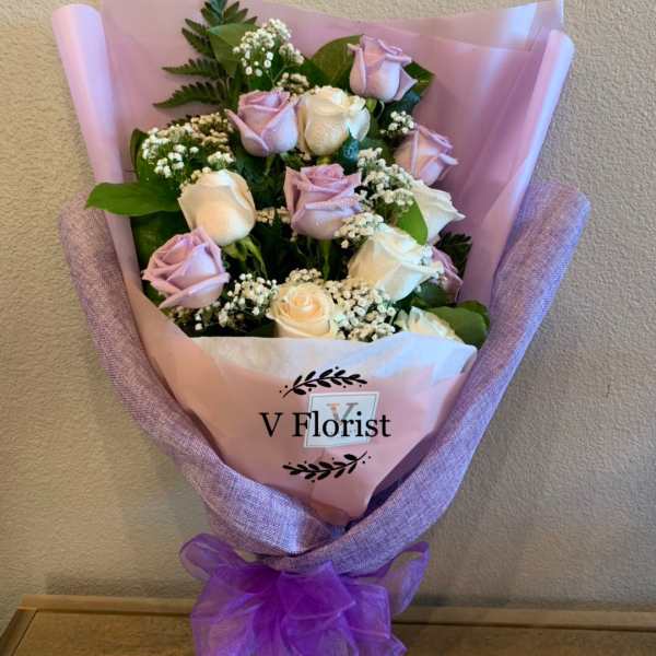 Bouquet of pale pink and white roses wrapped in pink paper