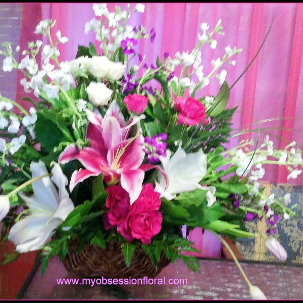 Basket arrangement with pink lilies, white blooms, and purple flowers
