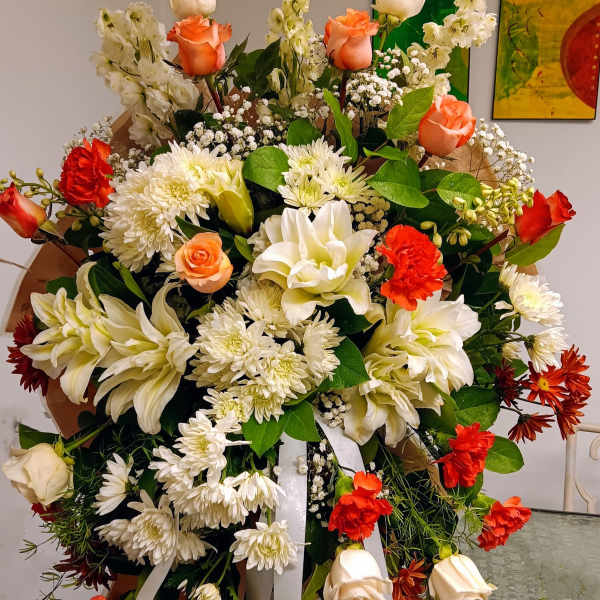 Large standing floral spray with white lilies, roses, and red carnations