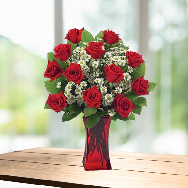 Red roses and white daisy-like flowers in a red glass vase