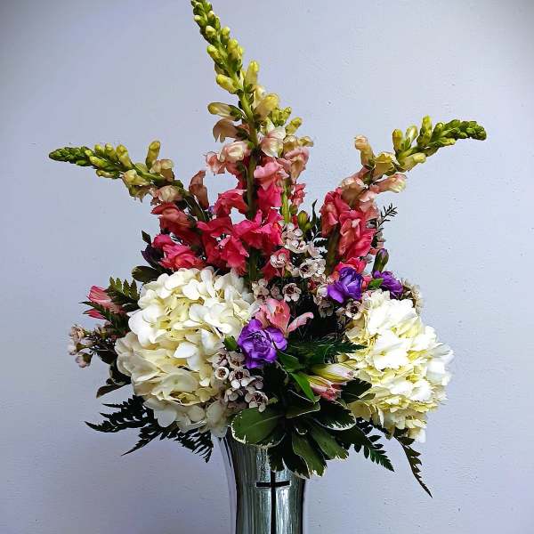 Tall floral arrangement in a silver vase with white, pink, and purple blooms