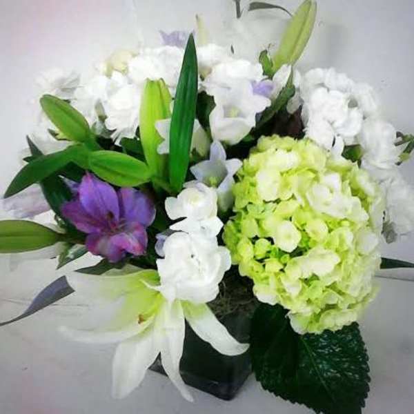Bouquet of white and purple flowers with green lilies in a black vase