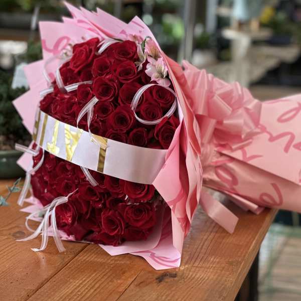 Bouquet of red roses wrapped in pink paper with ribbon