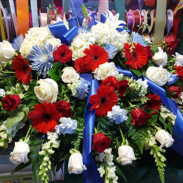 Large floral spray with red, white, and blue flowers and a blue ribbon
