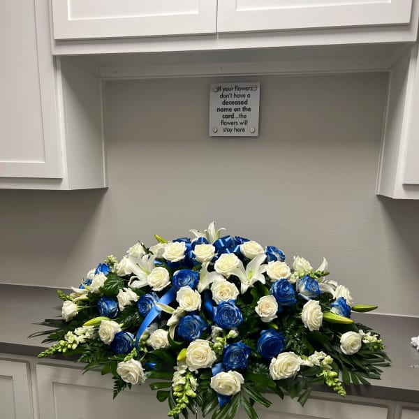 Large white and blue rose funeral spray with ribbon