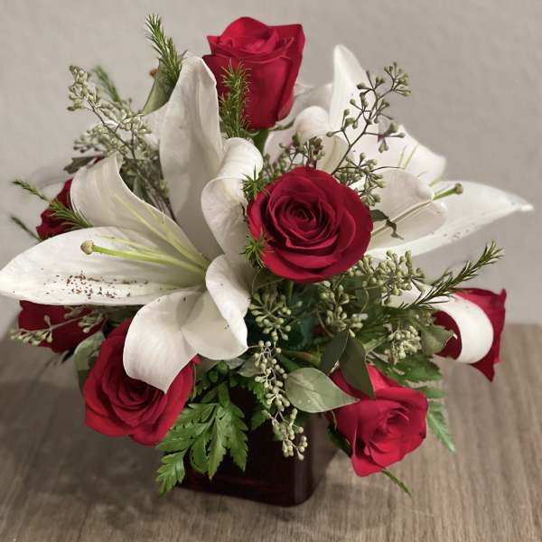 Bouquet of red roses and white lilies in a dark vase