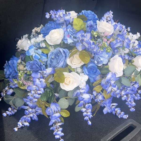 Blue and white rose bouquet with trailing blue flowers in a car trunk