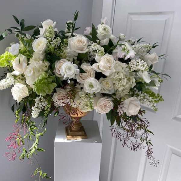 Large white floral arrangement in a gold vase