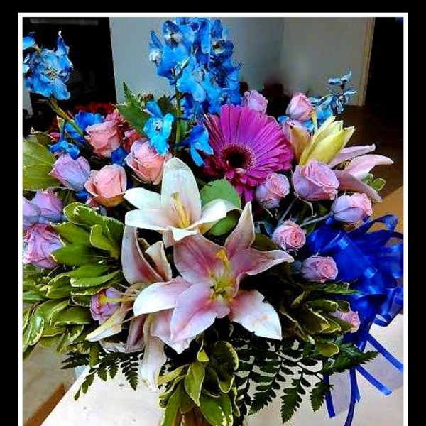Bouquet of lilies, roses, and a purple gerbera daisy in a glass vase