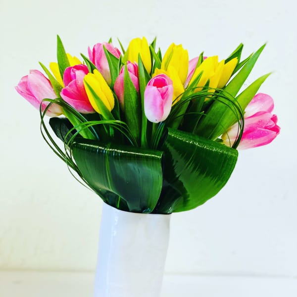 Bouquet of pink and yellow tulips in a white vase