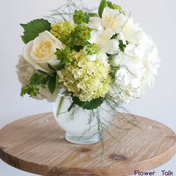 White and pale green floral arrangement in a glass vase