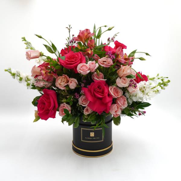 Pink and white mixed flower arrangement in a black hatbox