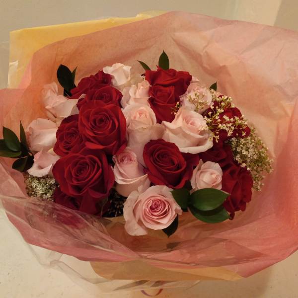 Bouquet of red and pale pink roses wrapped in pink paper