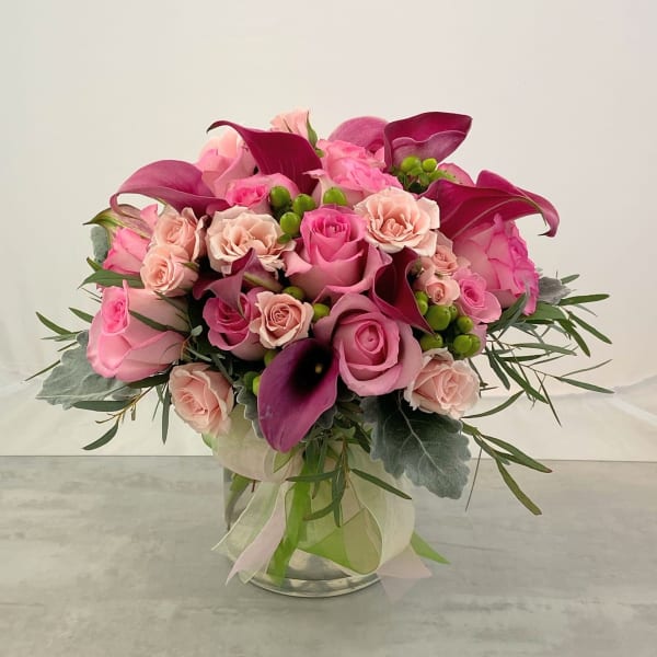 Pink and magenta bouquet with roses and calla lilies in a glass vase