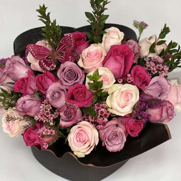 Bouquet of pink and lavender roses with a butterfly decoration in black wrap