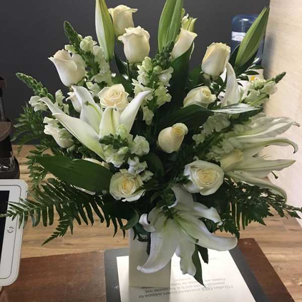 White roses and lilies arranged in a vase with greenery