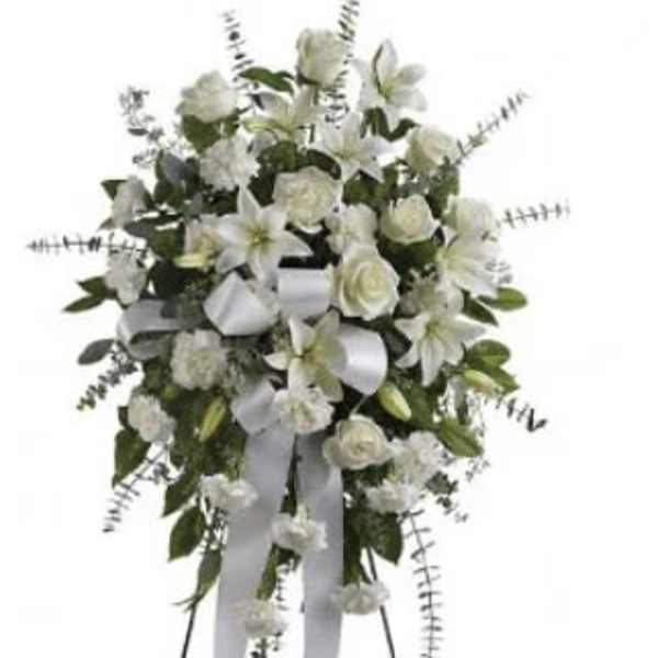 White floral standing spray with ribbon streamers on a stand