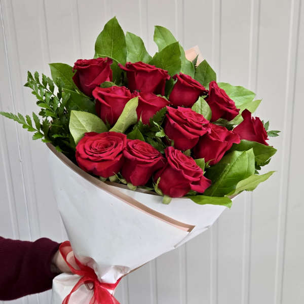 Bouquet of red roses wrapped in white paper with a red ribbon