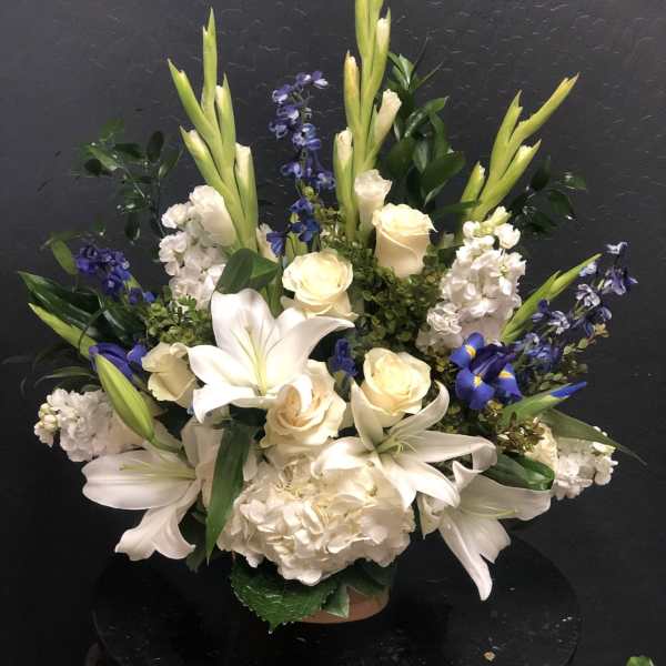 White lilies, cream roses, and blue flowers arranged in a vase