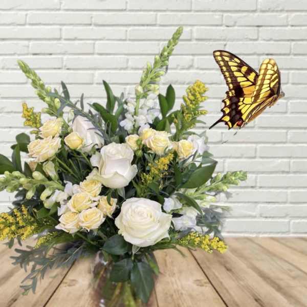 White and pale yellow flower arrangement with a butterfly decoration