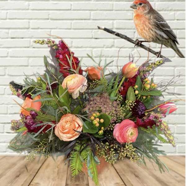 Mixed bouquet with peach and pink flowers and a bird figurine on a branch