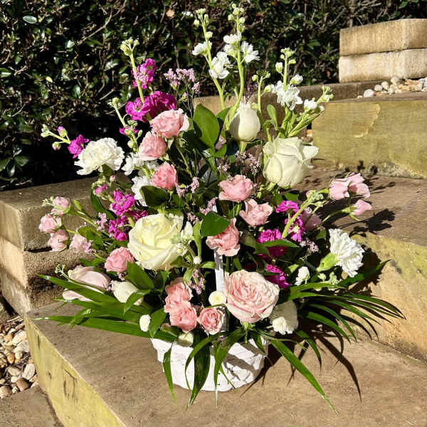 Pink and white floral arrangement in a white basket
