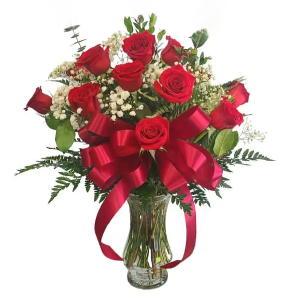 Red roses arranged in a clear glass vase with a large red ribbon