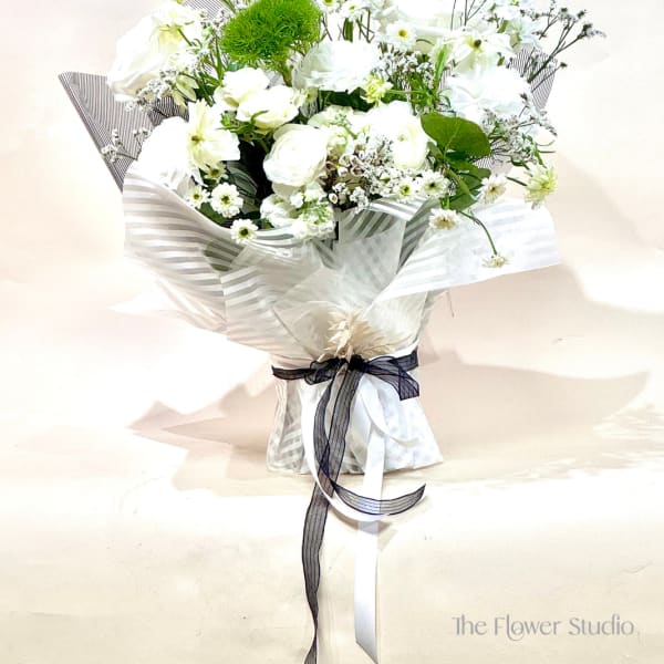 White bouquet with roses and small daisies wrapped in striped paper