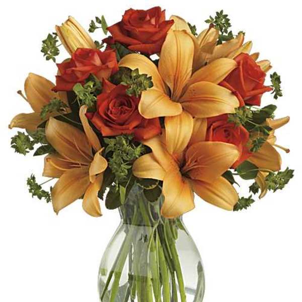 Arrangement of orange lilies and red-orange roses in a clear glass vase