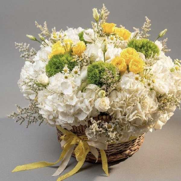 Basket arrangement of white and yellow flowers with green accents