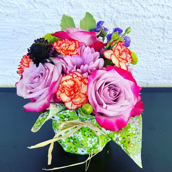 Bouquet of pink roses and mixed flowers in a green patterned wrap