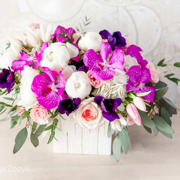 Pink, white, and purple floral arrangement in a white wooden box